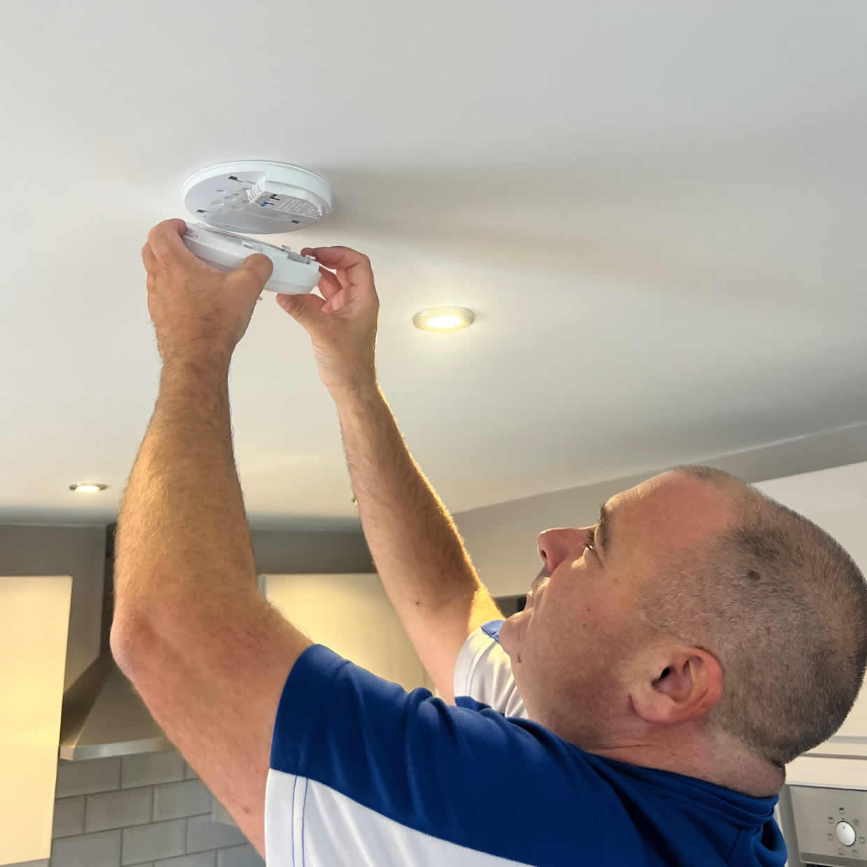 Smoke alarm installer fitting an alarm in a Carlisle property